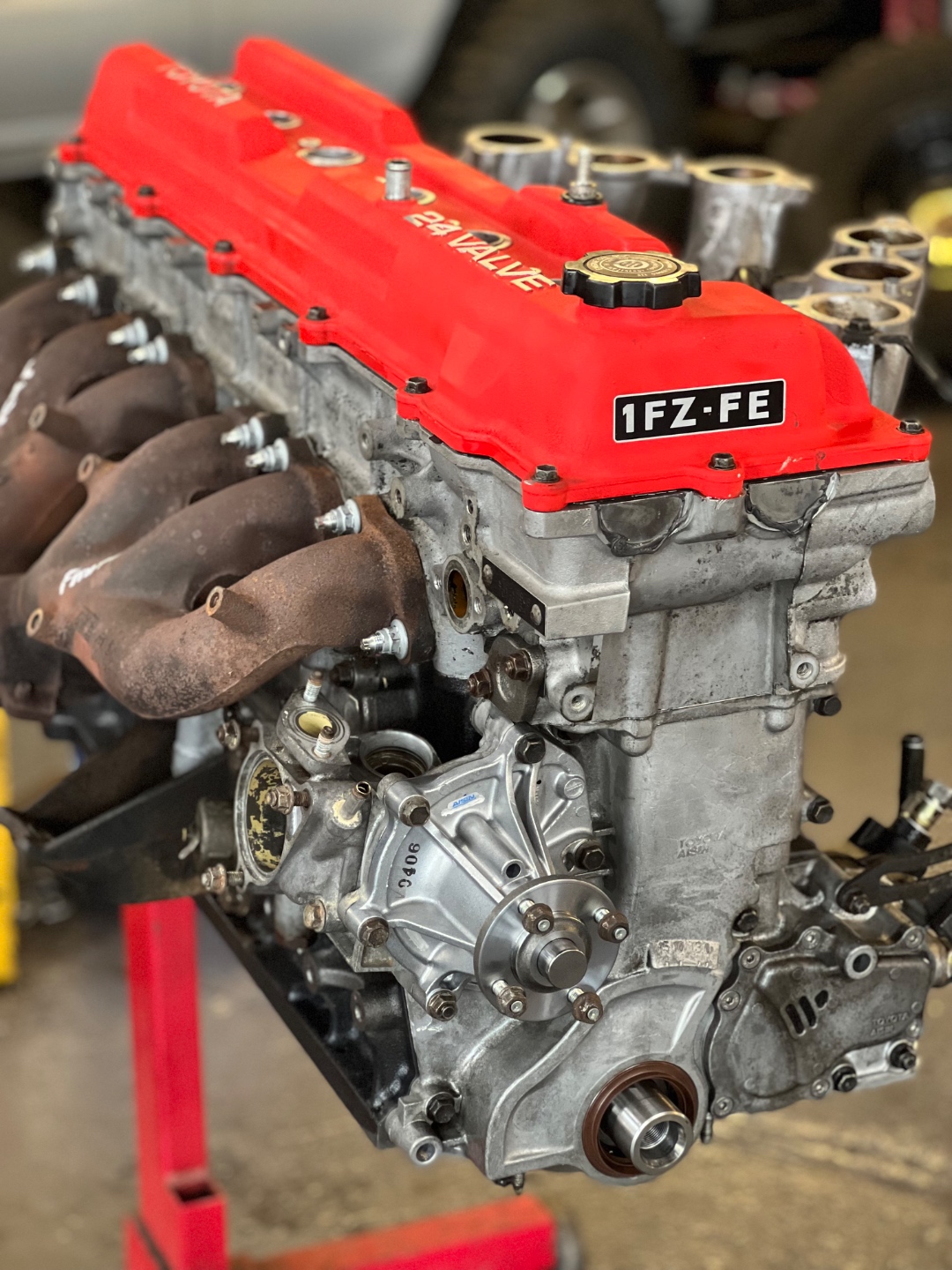 1FZ-FE engine with red valve cover on engine stand — 24-valve inline-six Land Cruiser
